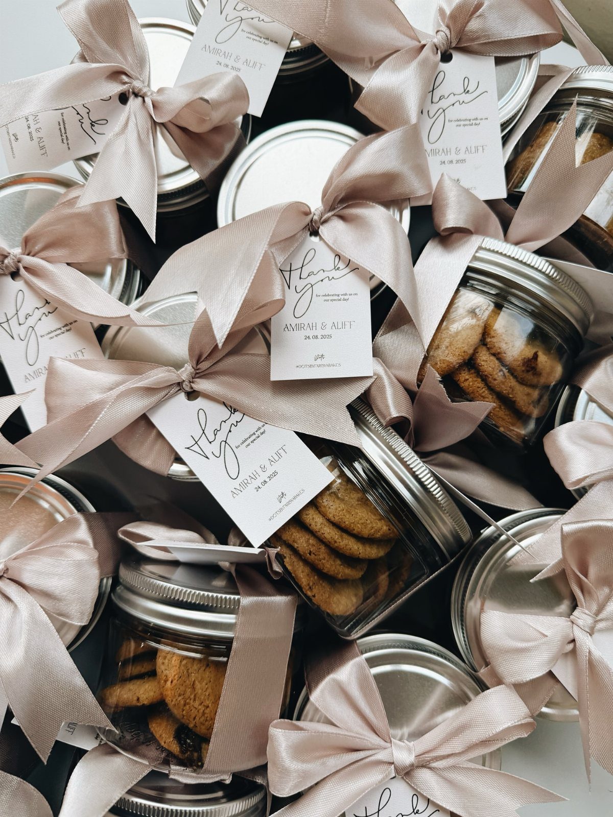 Small mason jars filled with mini cookies, tied with champagne satin ribbons.