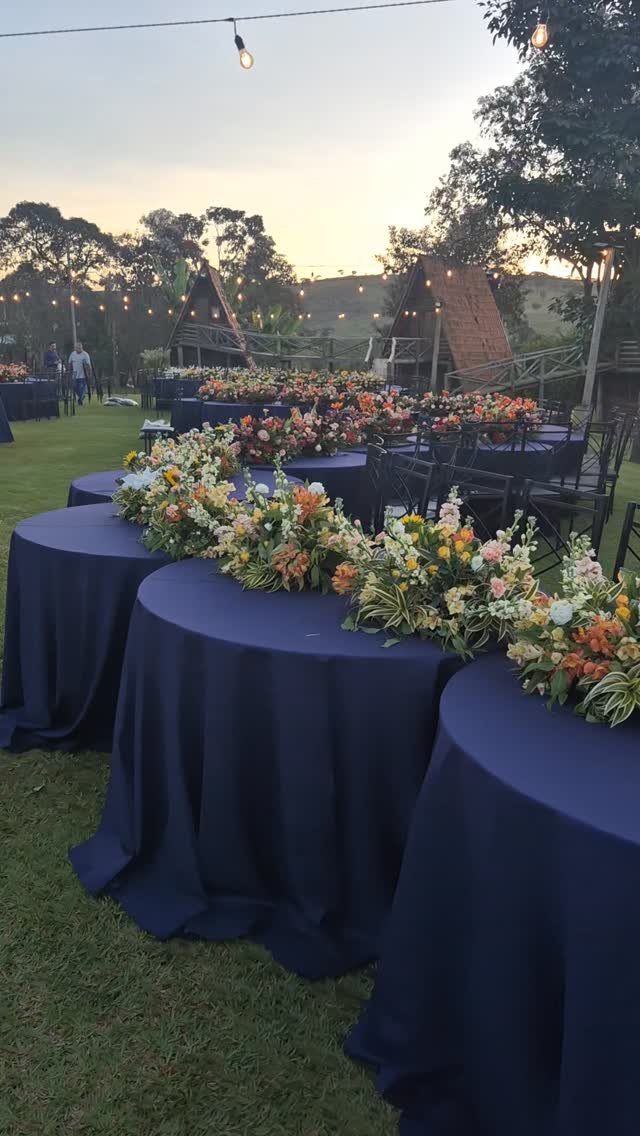 Navy blue table linens with long floral arrangements of white and orange flowers.