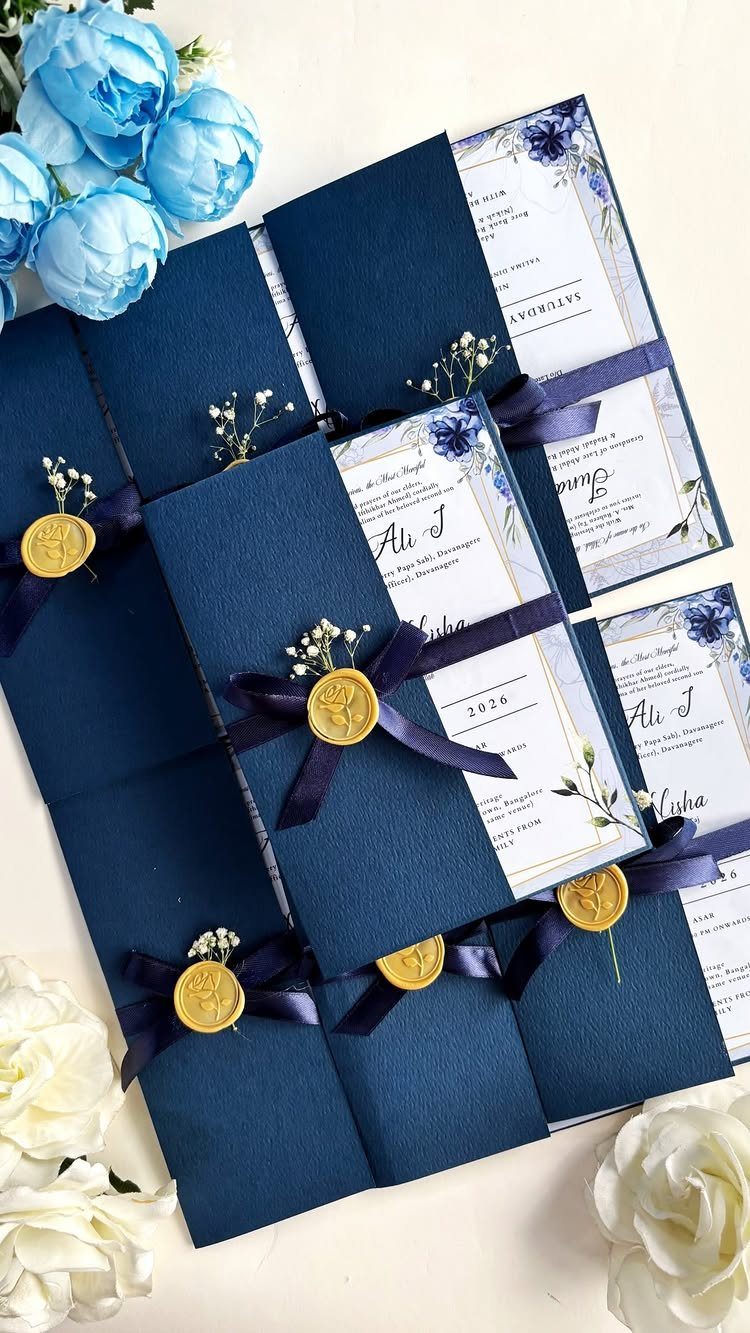 Navy blue wedding invitations with gold wax seals, navy ribbons, and blue floral accents.