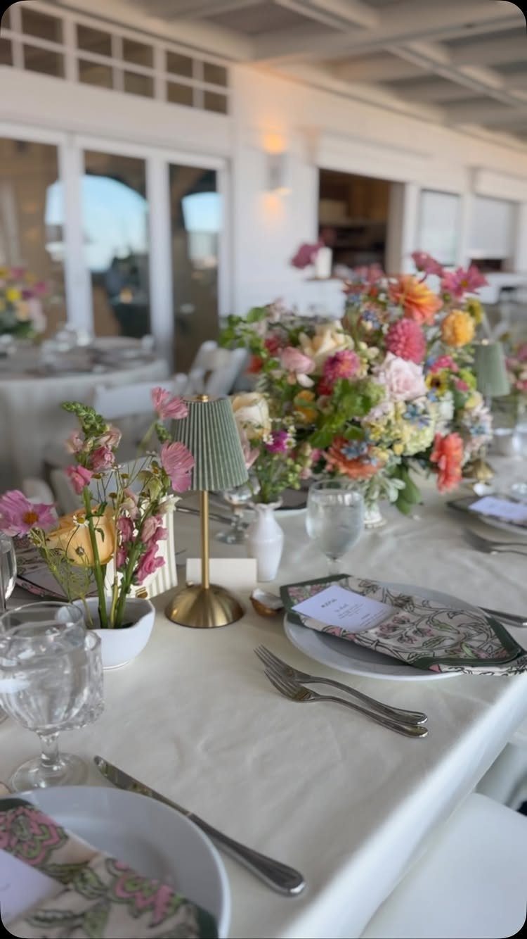 Wedding table setting with white linens, pastel floral centerpieces, and elegant dinnerware.