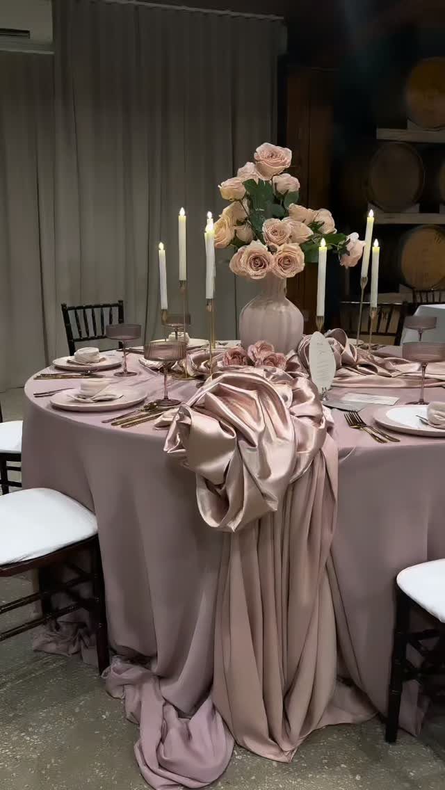 Dusty rose satin table setting with pink roses and white taper candles