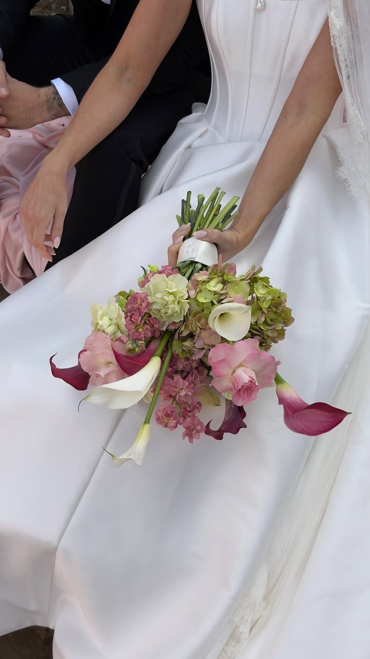 Bridal bouquet with pink roses and green hydrangeas held against a white dress