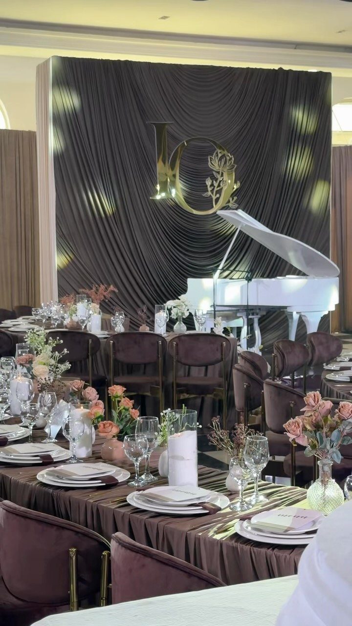 Chocolate brown table settings and draped backdrop with a white grand piano.