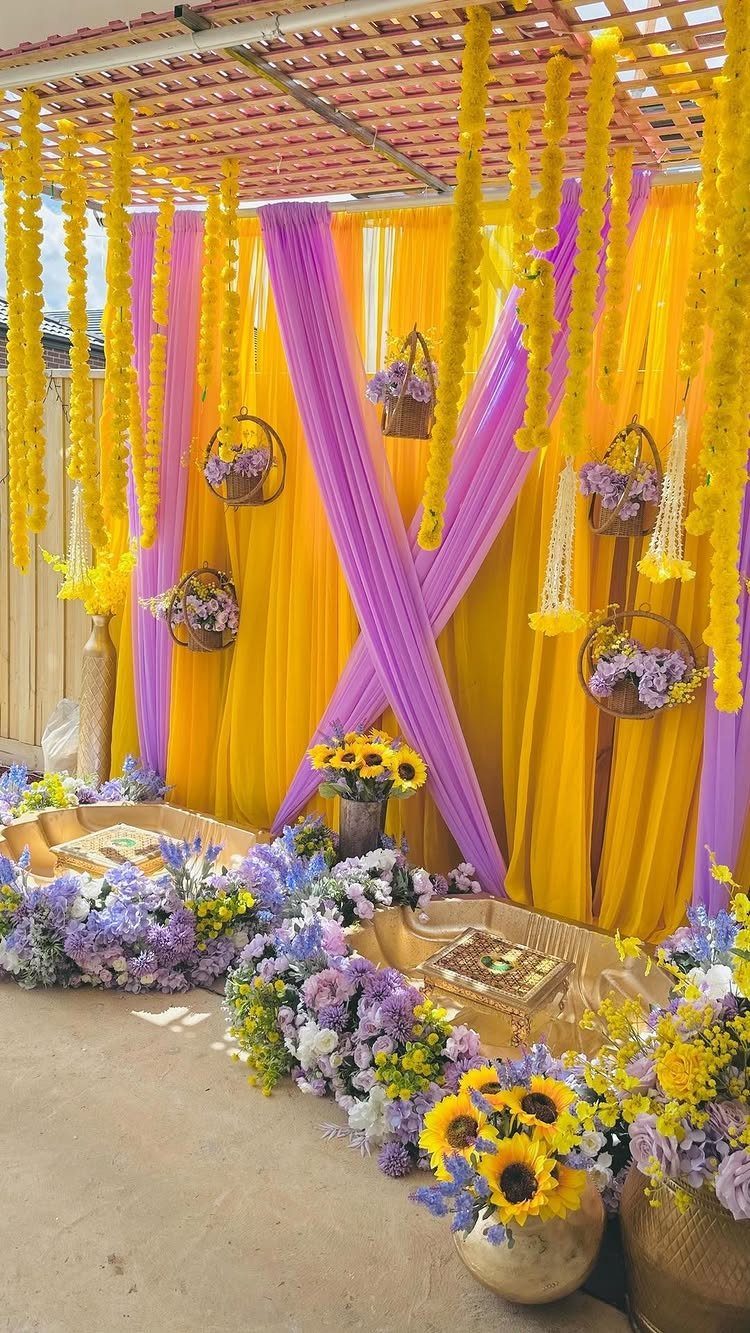 Yellow and purple fabric backdrop with sunflowers and purple floral arrangements for a wedding.