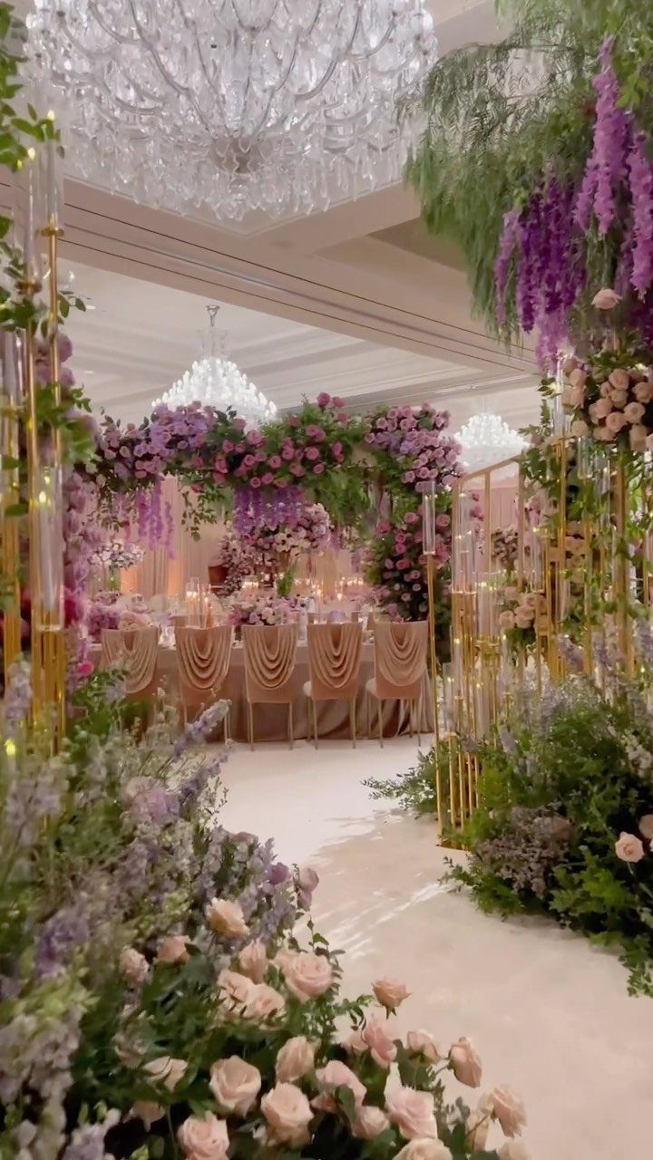 Lavish wedding venue with gradient purple floral arrangements and gold decorative structures.