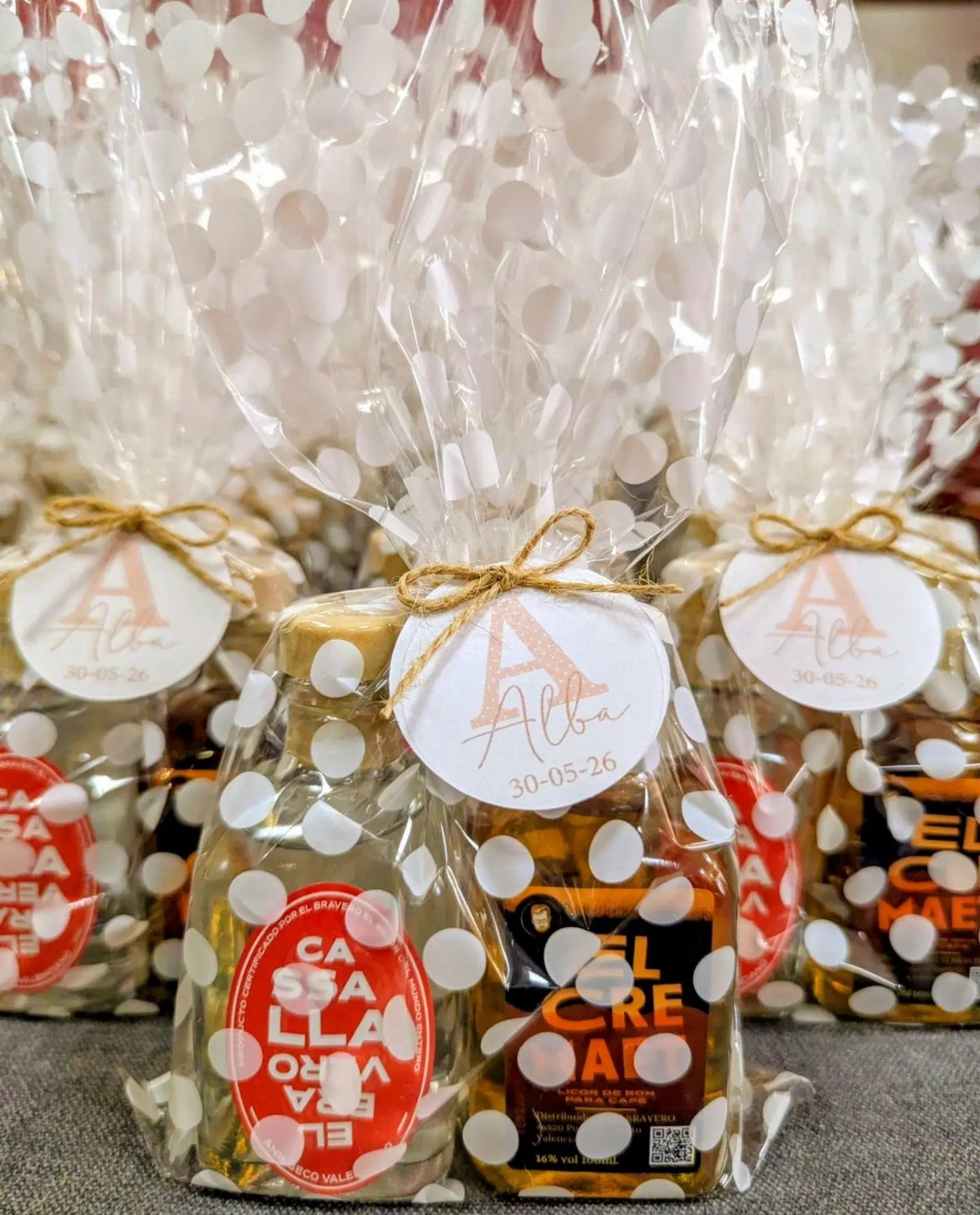 Miniature alcohol bottles in polka-dot cellophane bags with personalized wedding tags.