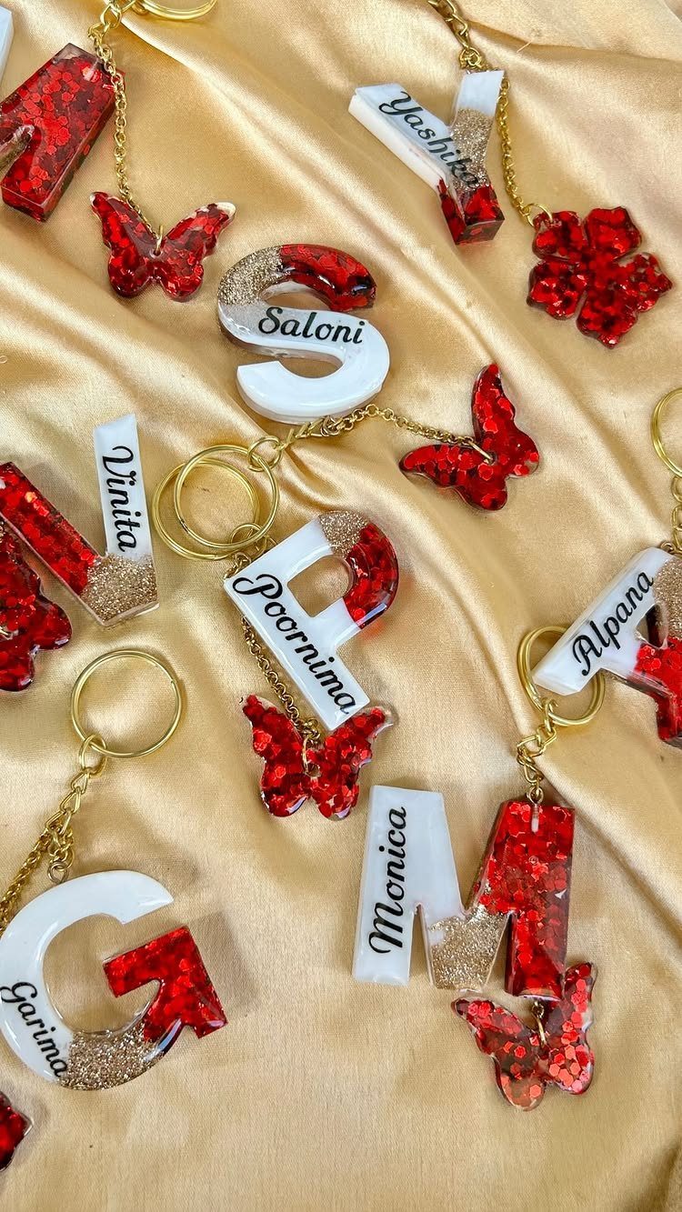 Resin keychains with names and red butterflies on gold satin fabric.
