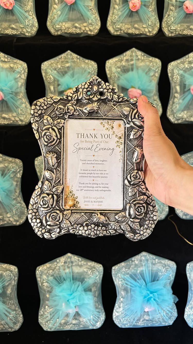 Ornate silver photo frame with thank you card held over wrapped gift frames.