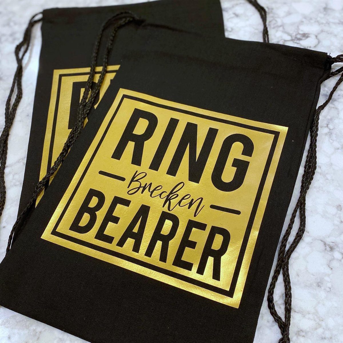 Black drawstring bags with gold foil Ring Bearer text and personalized name.