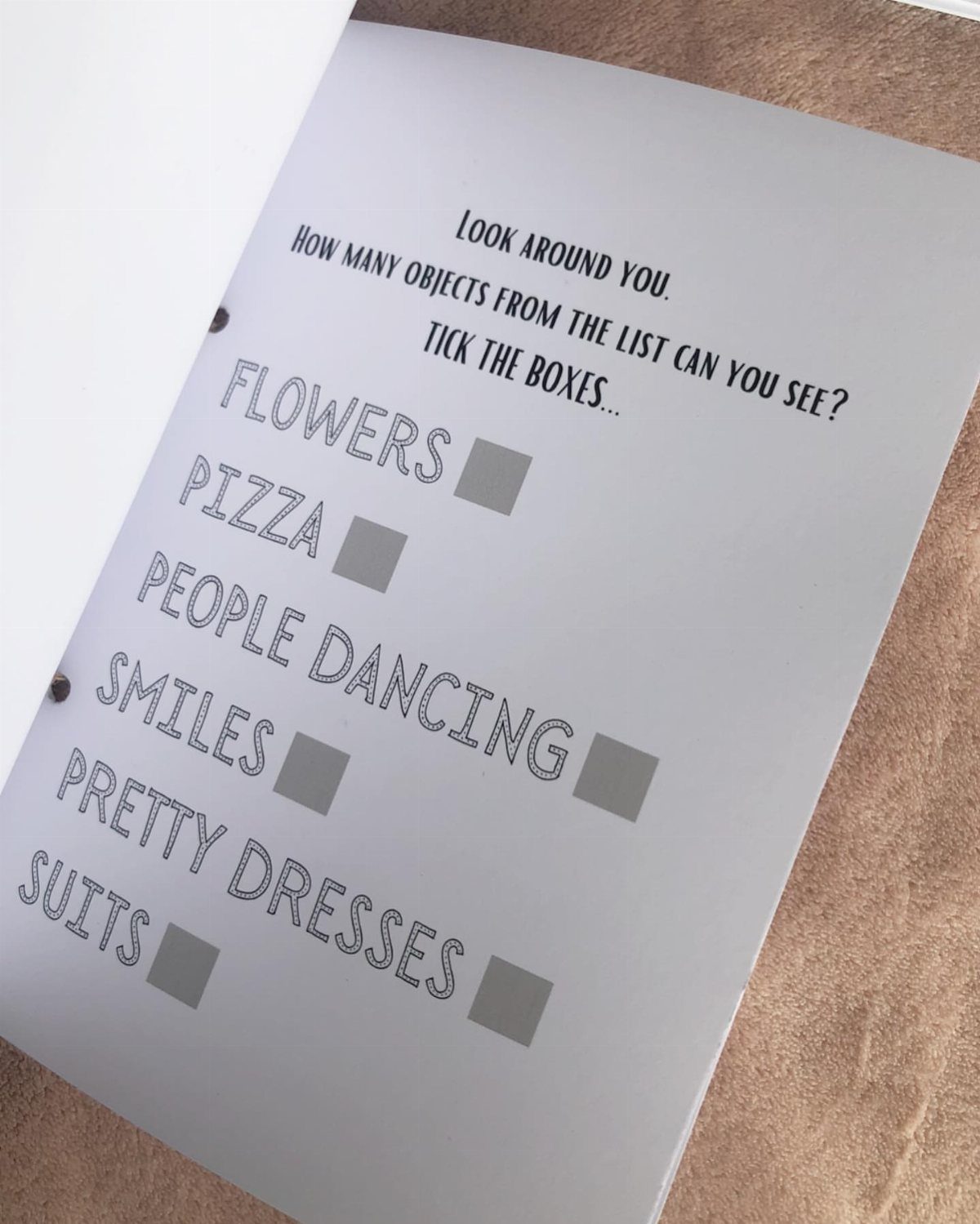 Scavenger hunt checklist in a white booklet for a wedding guest activity.