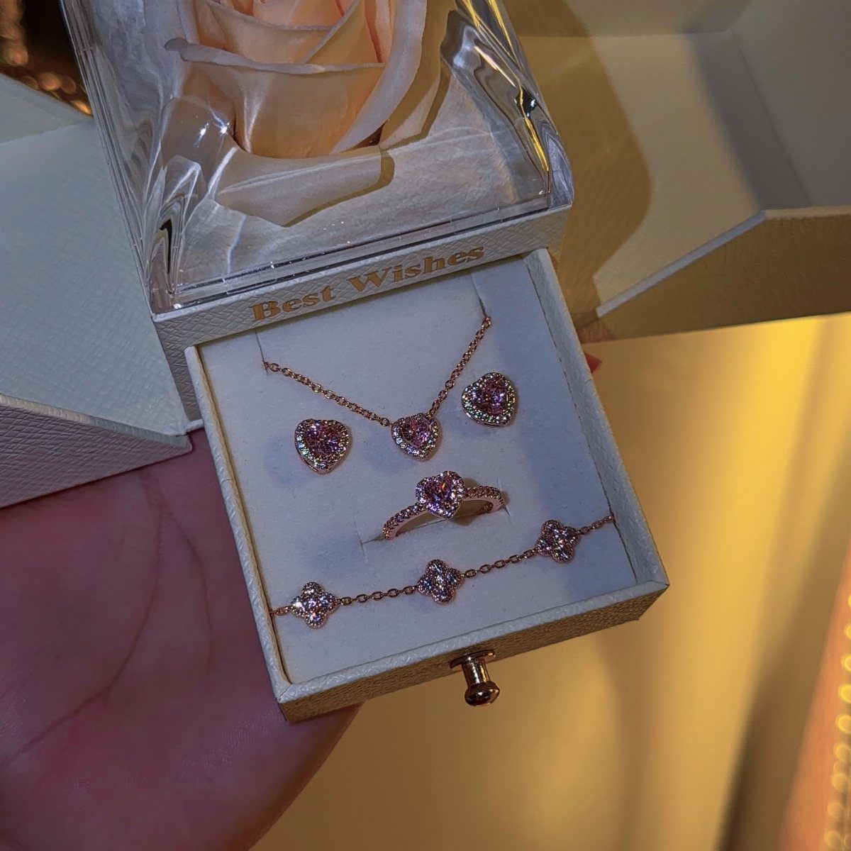 Rose gold heart-shaped jewelry set in a white box with a pink rose.