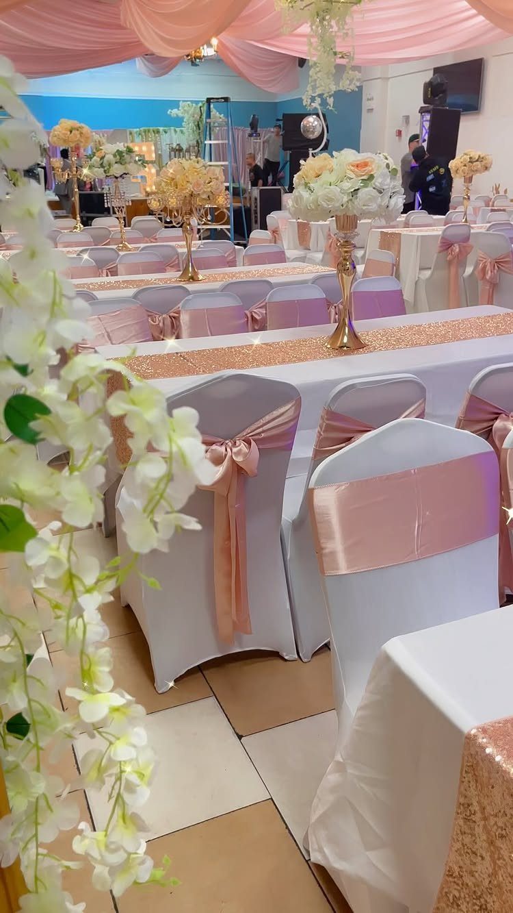 Tall gold vases with white flowers as centerpieces on rose gold sequin tables.