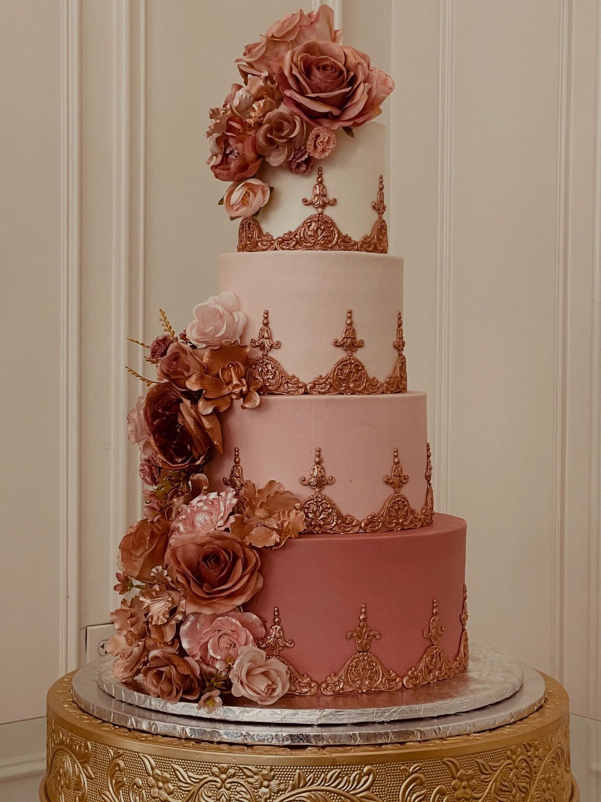 Four-tier ombre rose pink wedding cake with gold filigree and sugar roses.
