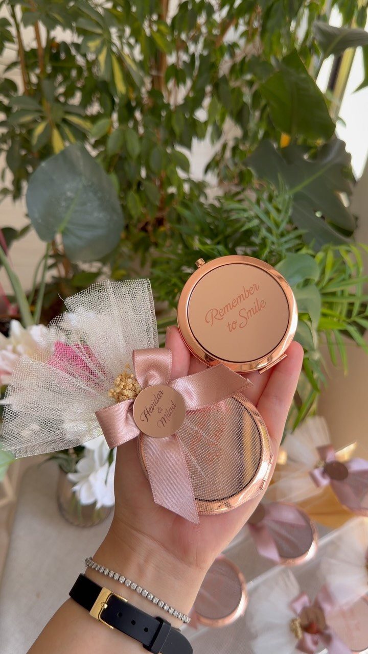 Rose gold compact mirror with pink bow and tulle as a wedding favor.
