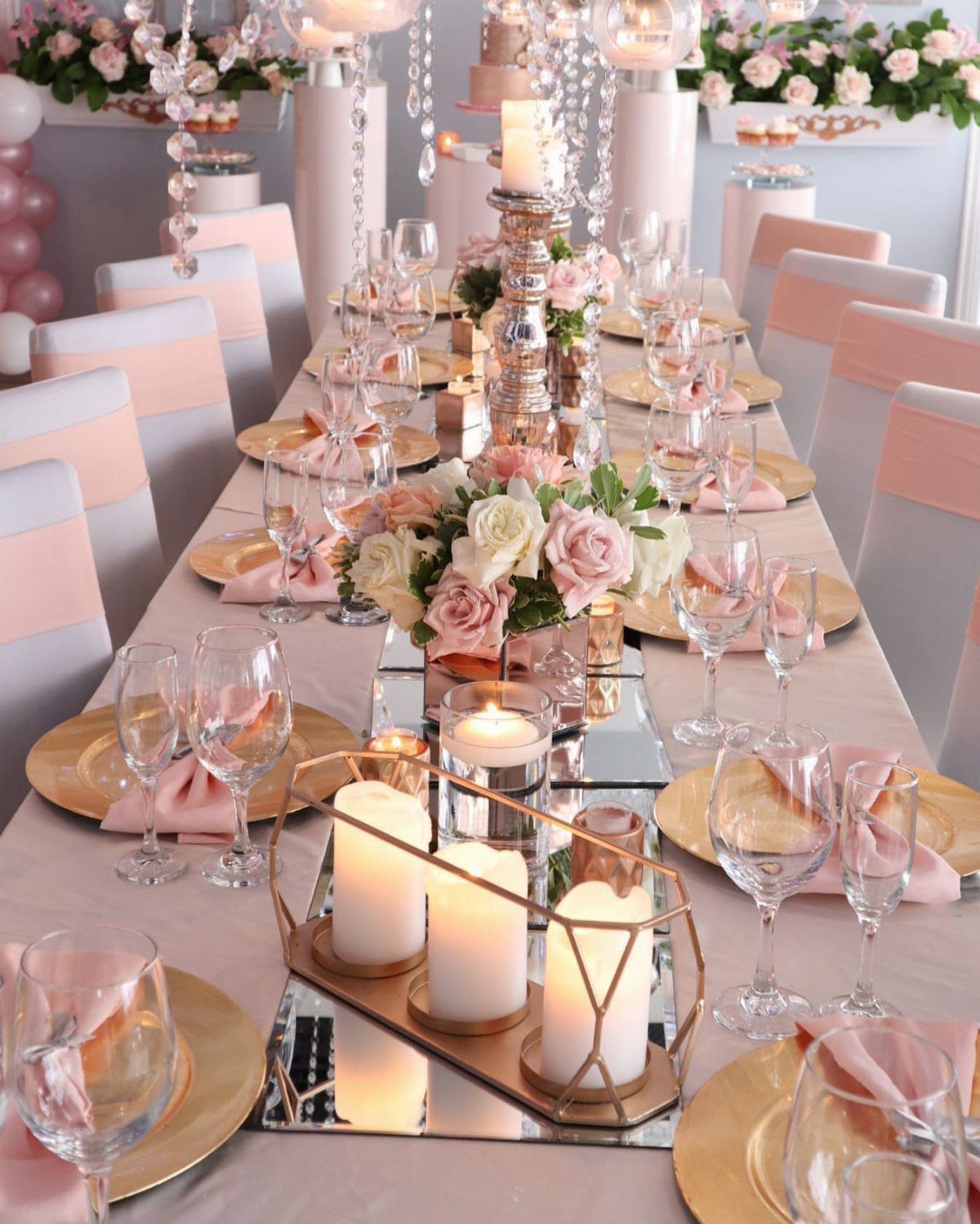 Elegant wedding table setting with rose gold accents, pink roses, and mirrored runners.