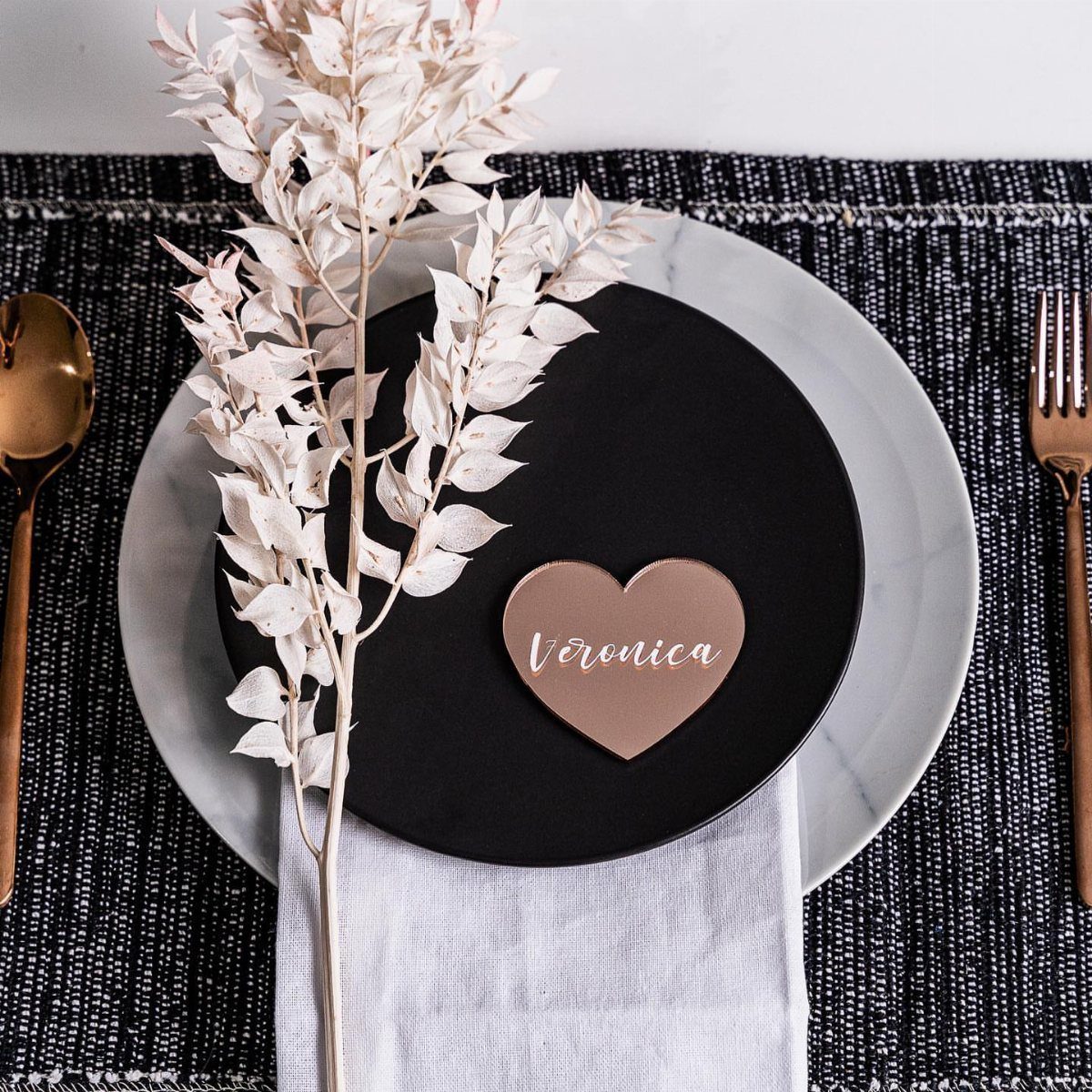 Table setting with marble plate, black charger, and rose gold heart name card.