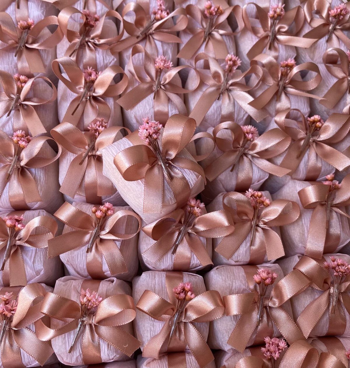 Rose gold wrapped gift parcels tied with satin bows and small pink flowers.