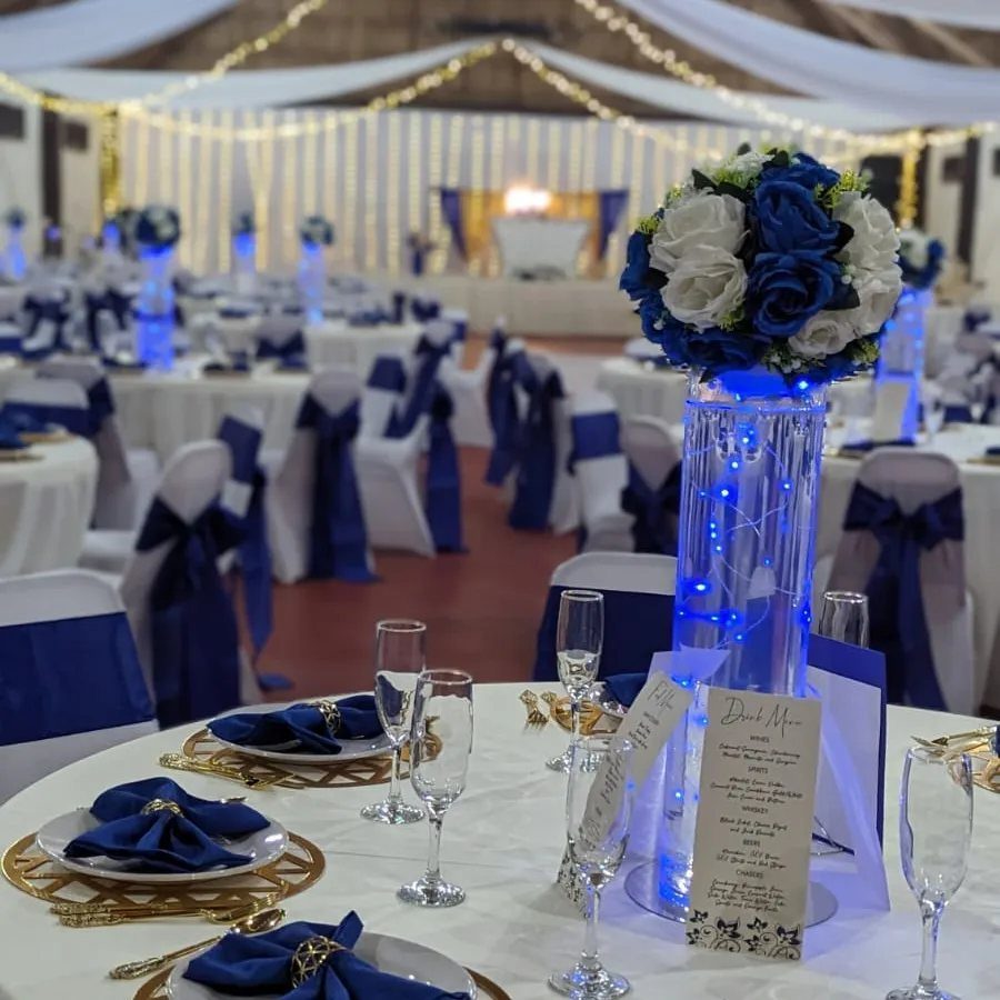 Royal blue and gold table settings with blue floral centerpieces in a wedding hall