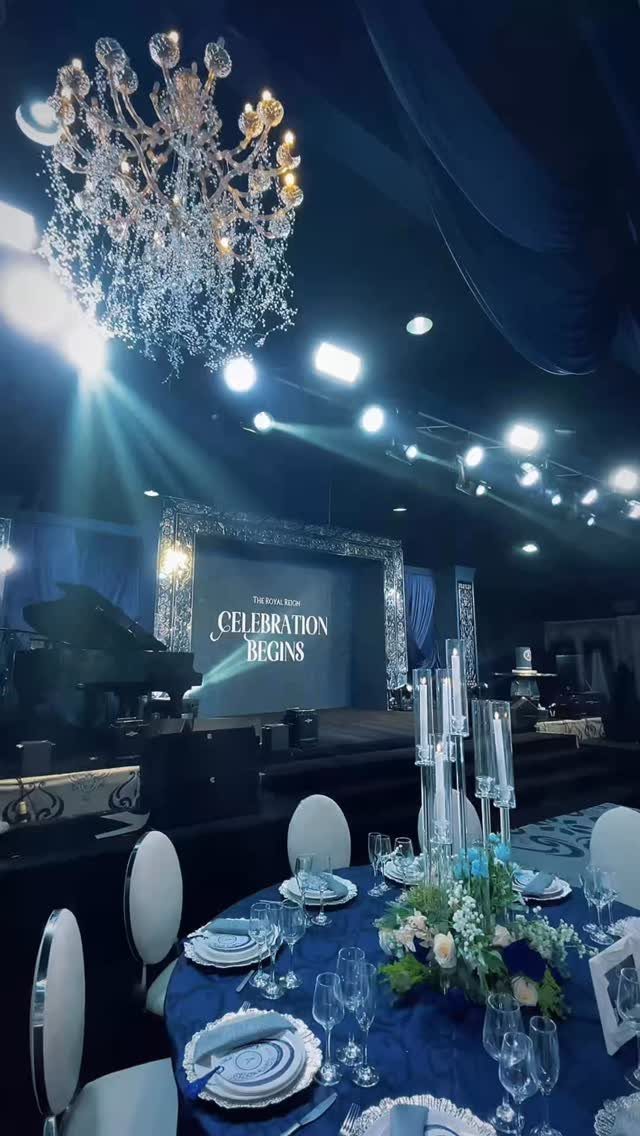 Royal blue table setting with white flowers under a large crystal chandelier.