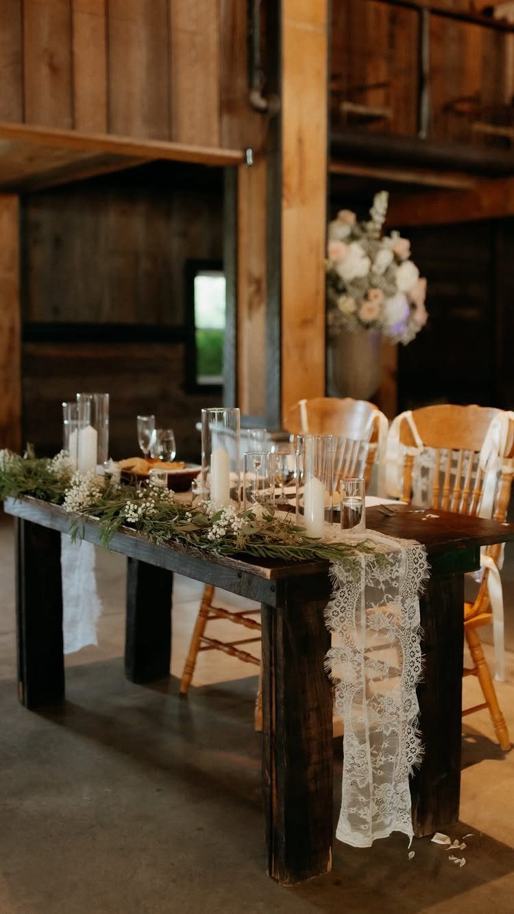 Wooden wedding table with lace runner, greenery garland, and baby's breath flowers.