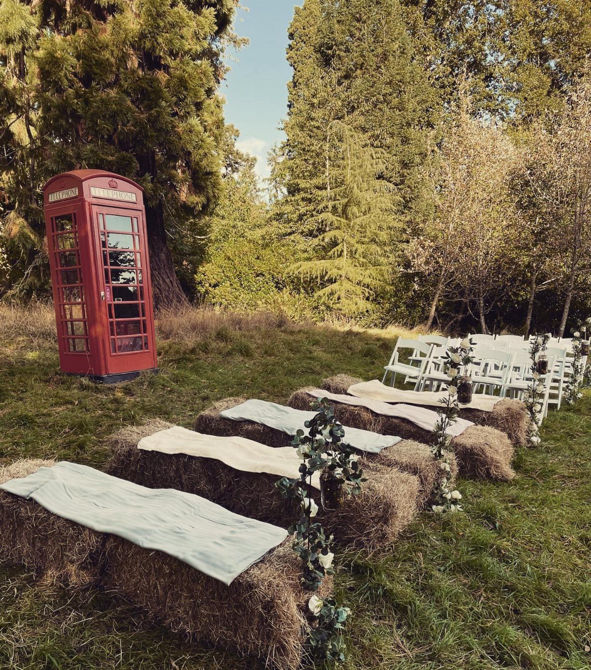 Hay bale seating covered in fabric in a field with a red telephone booth.