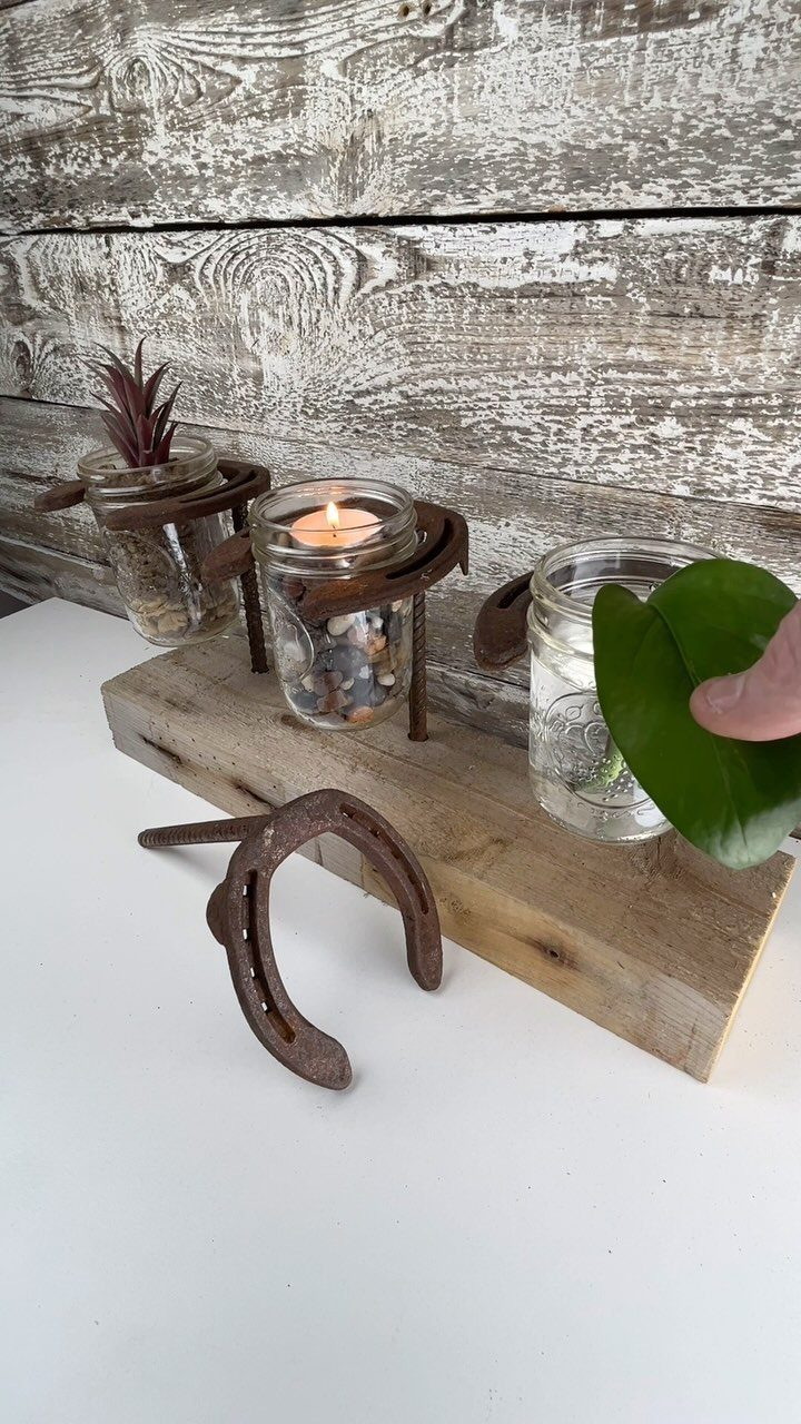 Mason jars with a candle and plant on a wooden beam with a horseshoe