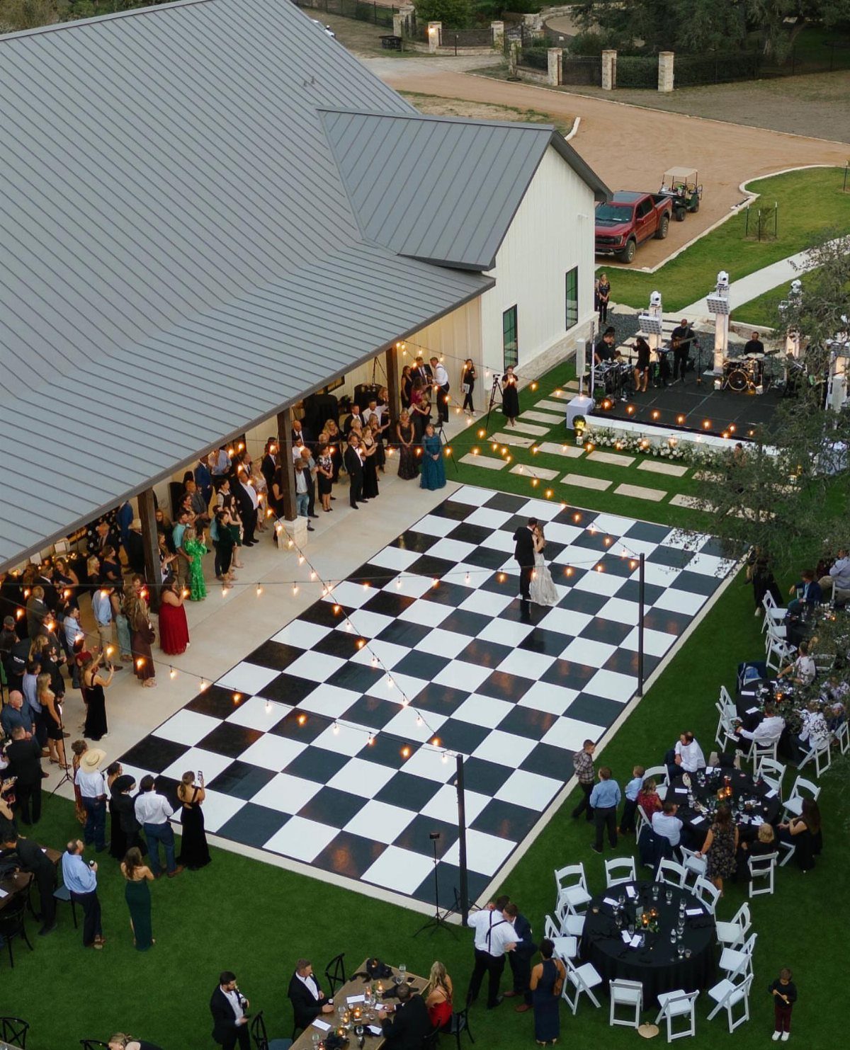 Black and white checkered dance floor at an outdoor wedding reception with guests.