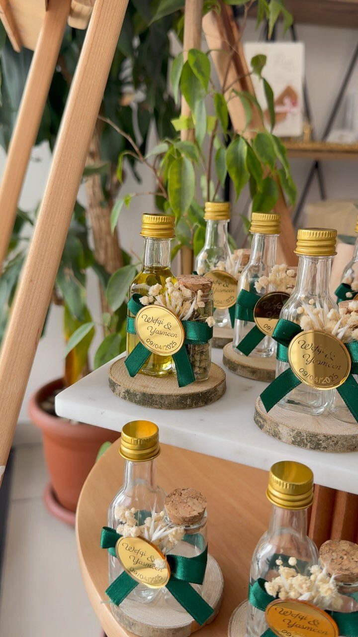 Small oil bottles with baby's breath and gold tags on wood slice coasters.