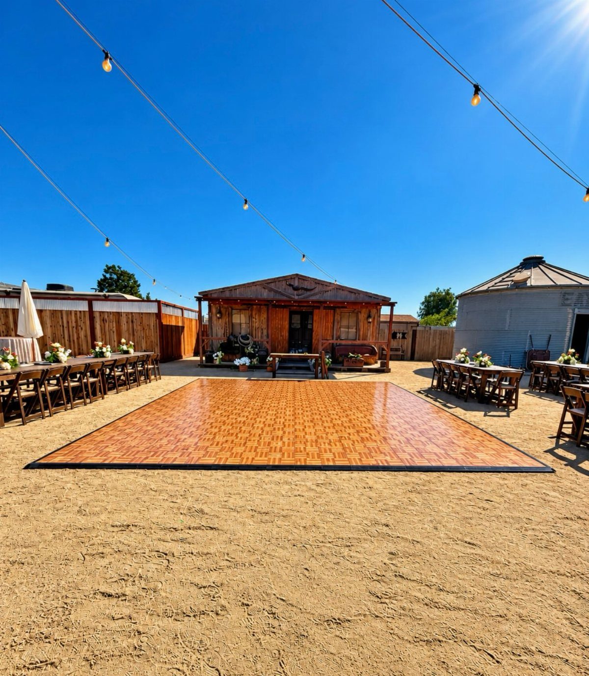 Polished wooden dance floor in a rustic outdoor wedding setting with string lights.