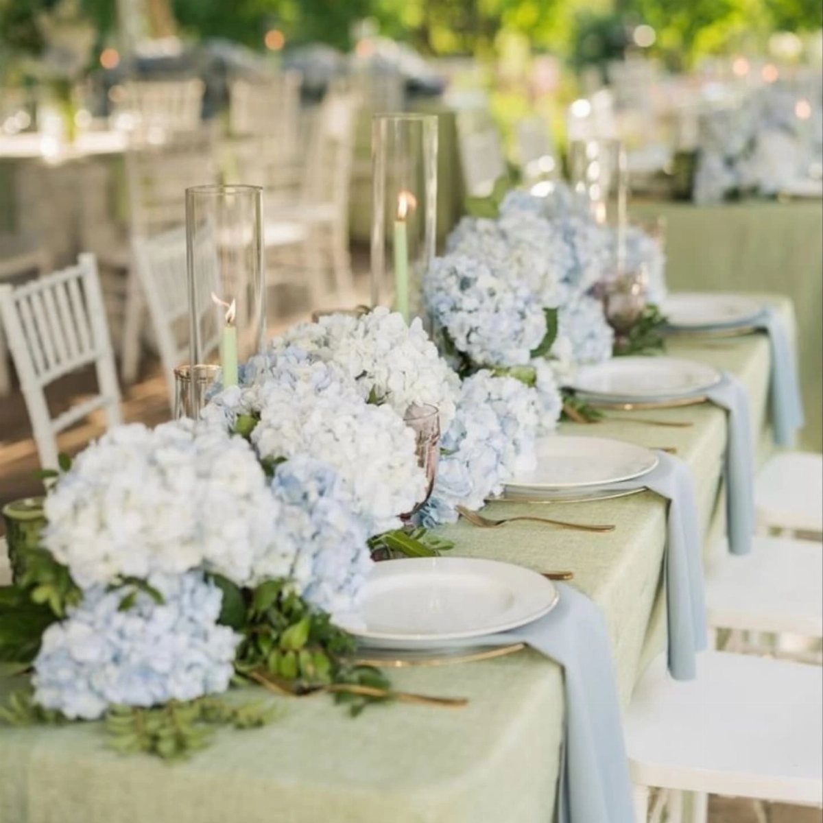 Sage green table setting with light blue napkins and blue hydrangea floral runner.