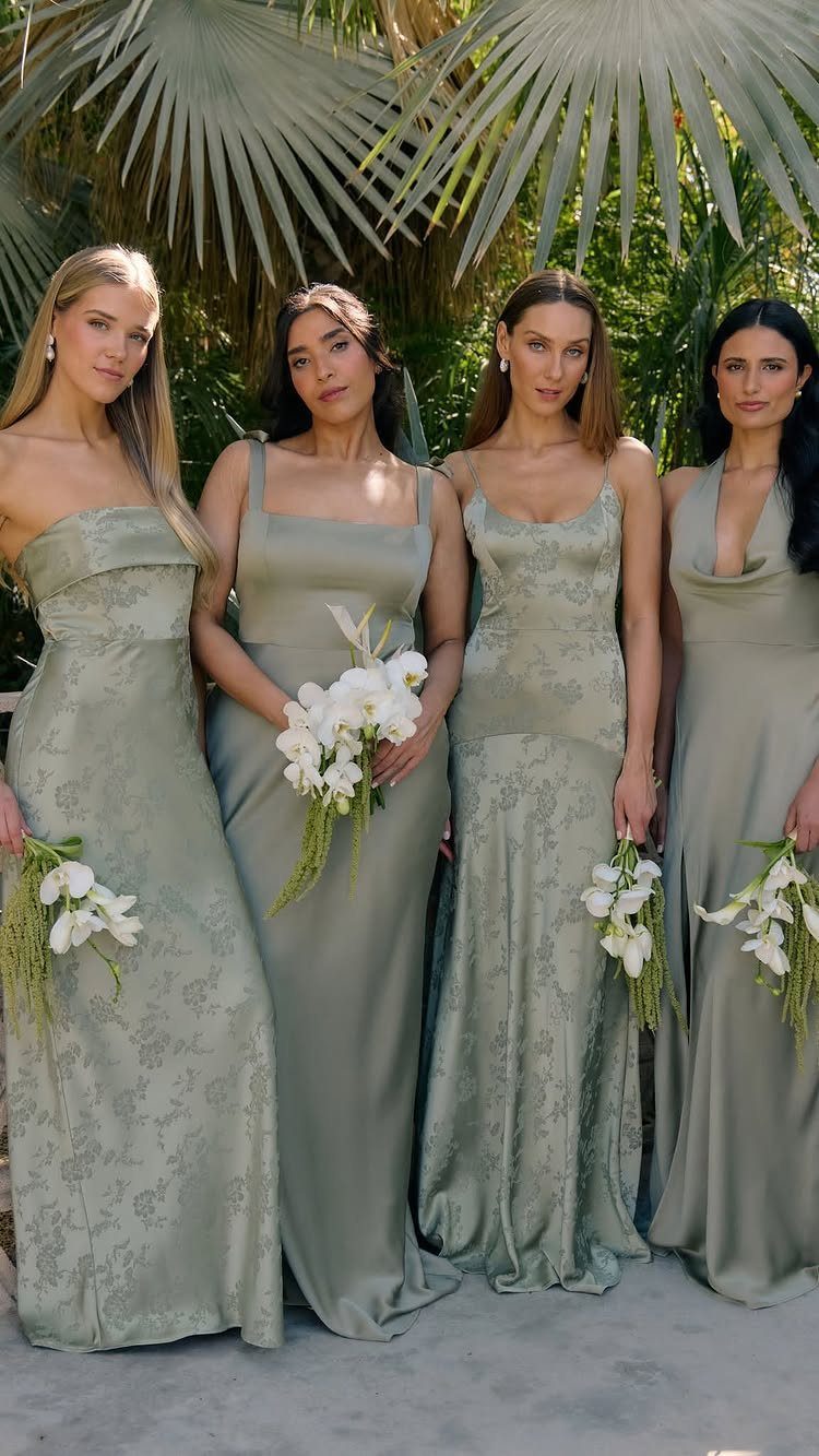 Four women wearing different styles of sage green bridesmaid dresses holding white bouquets.