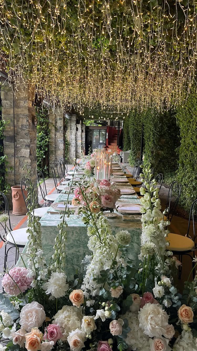Long wedding table with pink and white flowers under a canopy of fairy lights