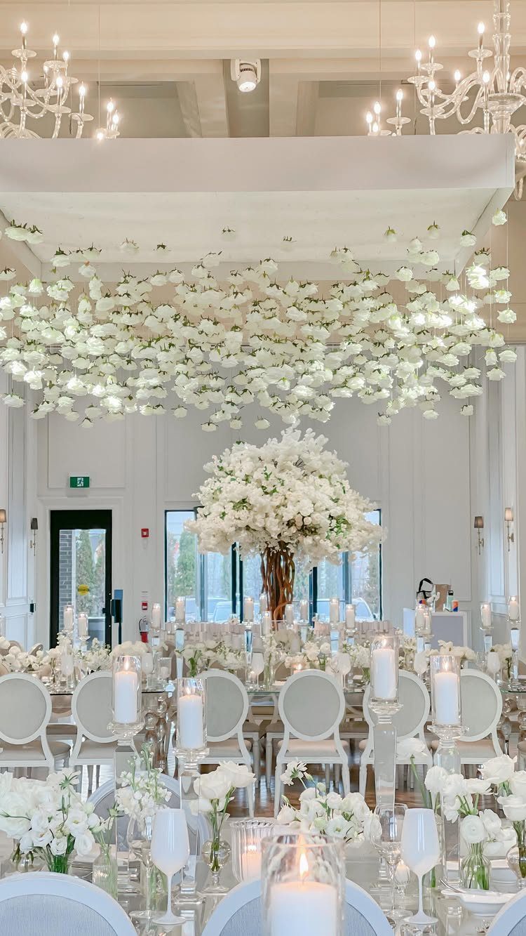 White floral installation suspended from the ceiling over an elegant wedding reception table