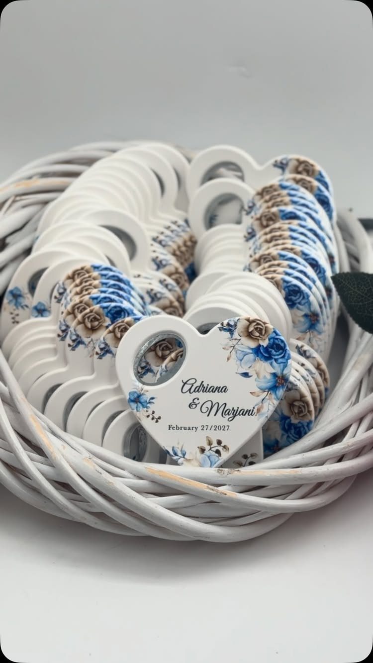 Heart-shaped white bottle openers with floral designs and names in a white basket.