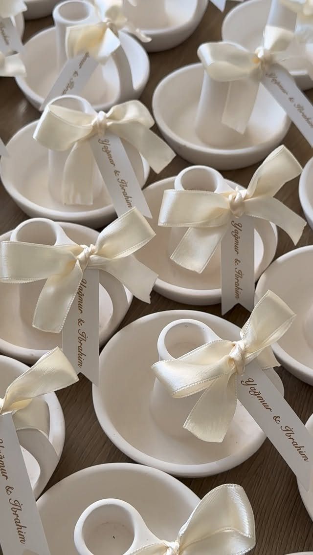White ceramic mini candle holders with cream satin bows and name tags.