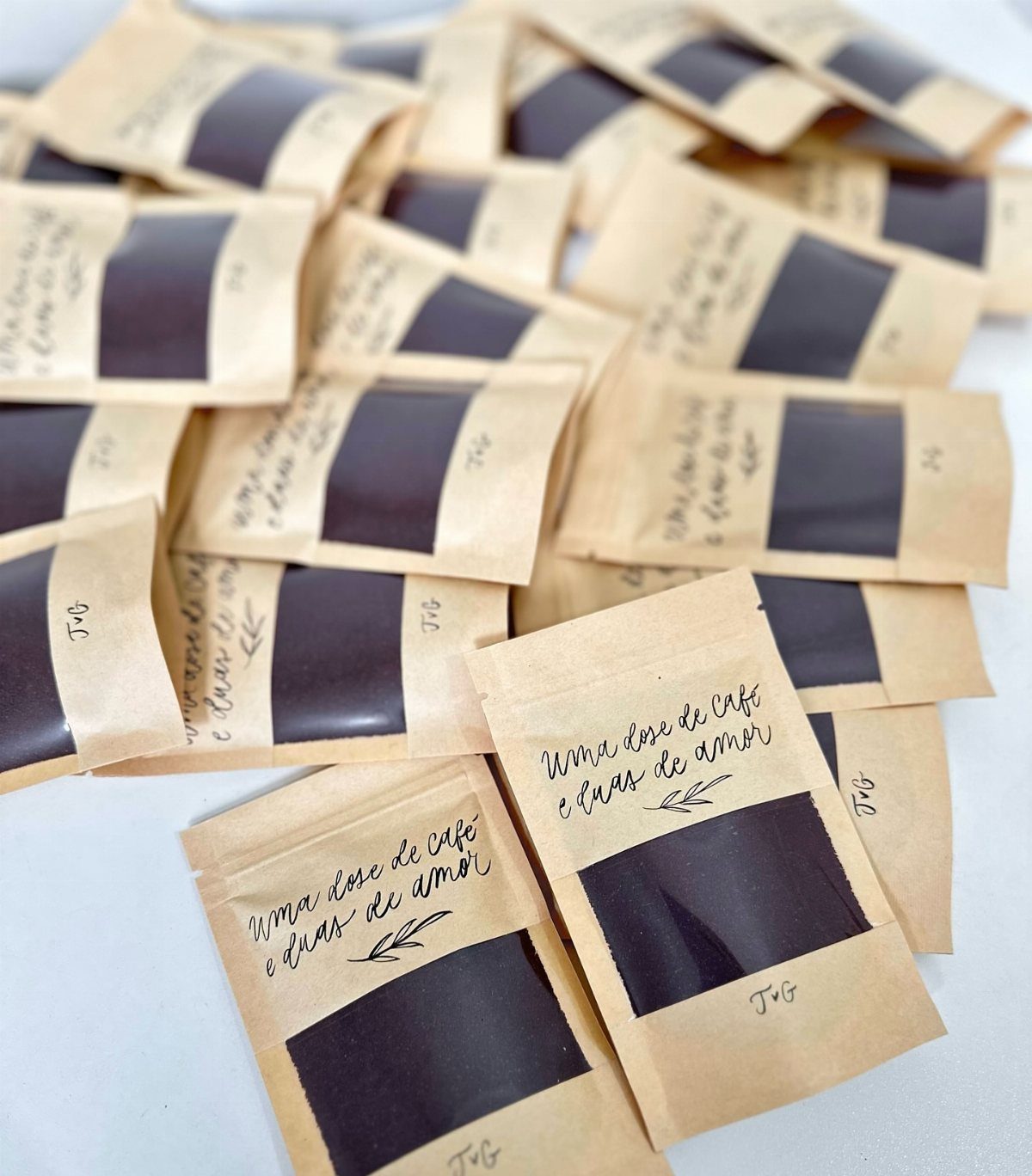 Brown kraft paper coffee packets with handwritten messages and clear windows showing grounds.
