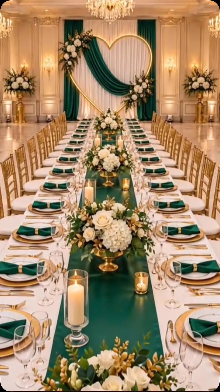 Long wedding table with green runner, white flowers, and gold accents in ballroom