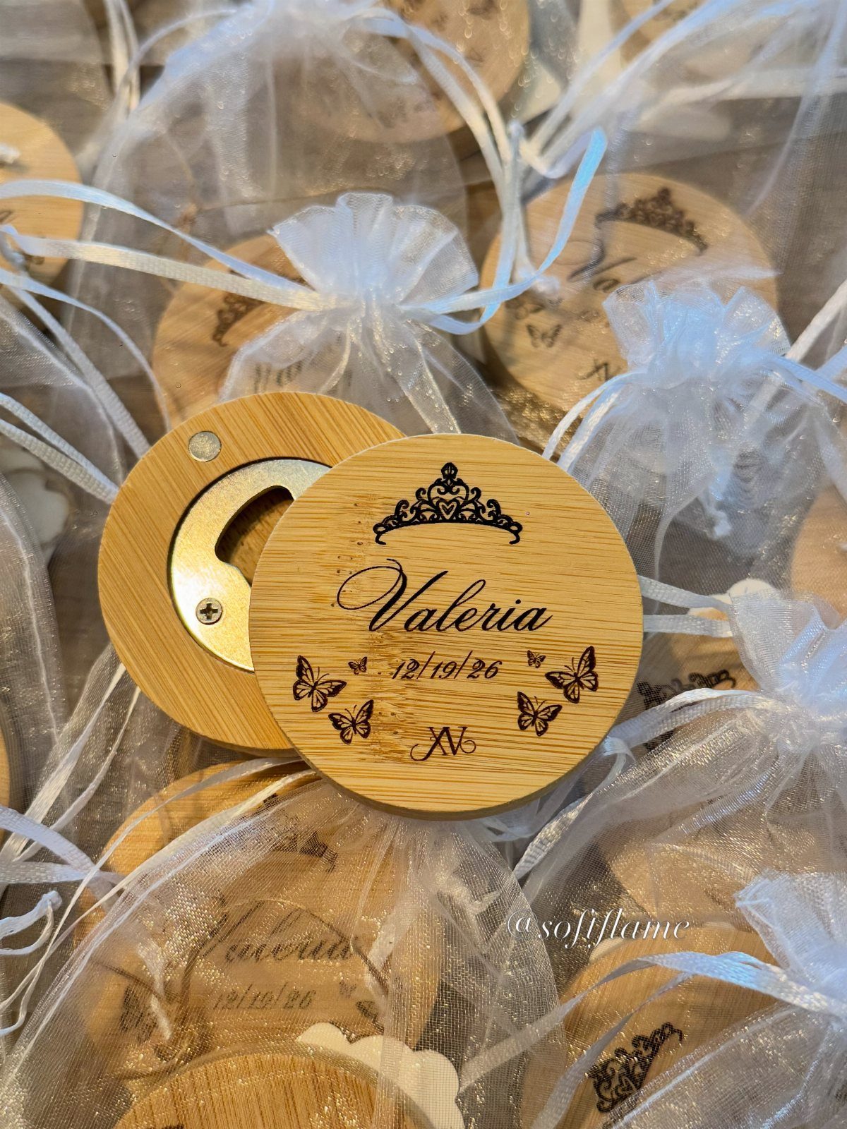 Engraved wooden bottle openers in white organza bags for wedding favors.