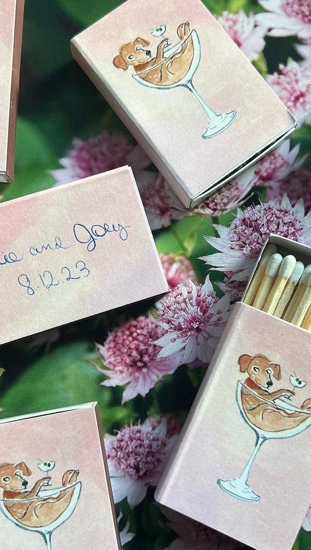 Custom pink matchboxes with dog illustrations scattered among pink flowers and green leaves.