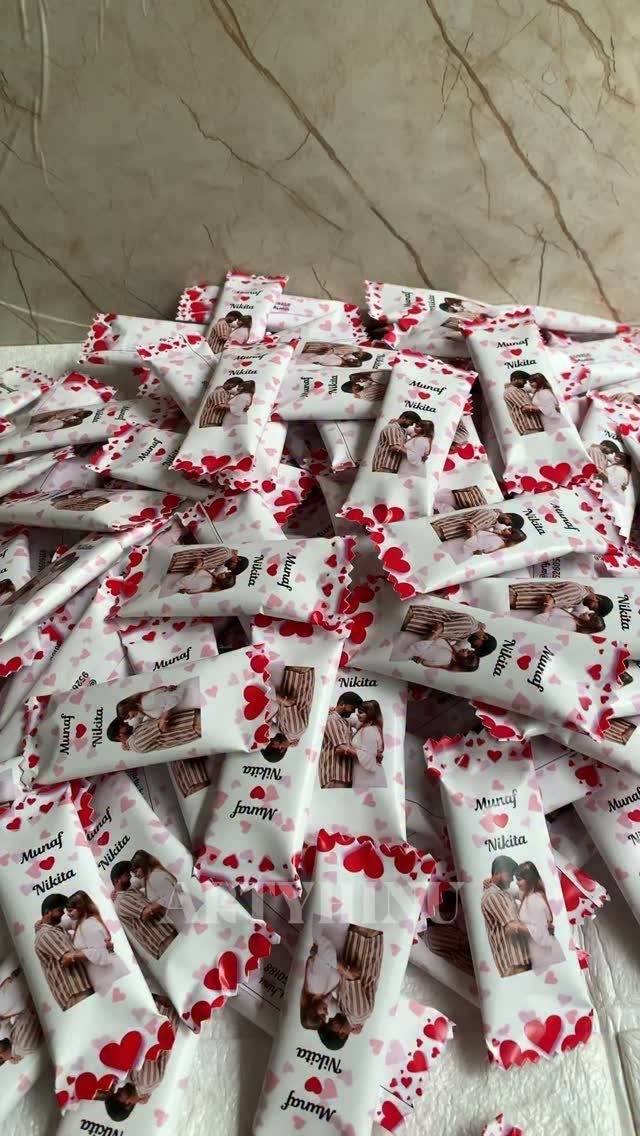 Customized chocolate bars with photo wrappers and red hearts piled together.