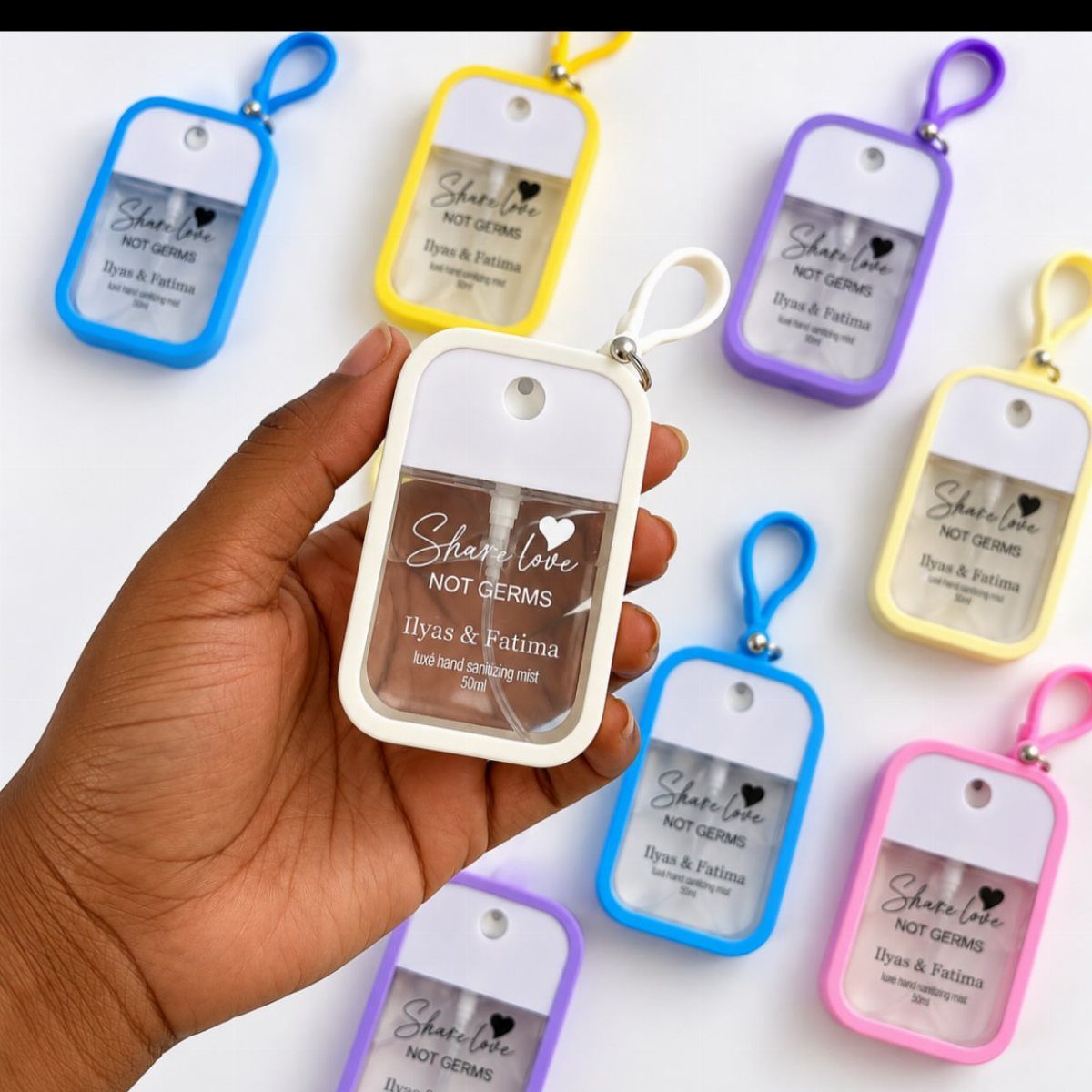 Personalized hand sanitizer spray bottles in colorful silicone cases for wedding favors.