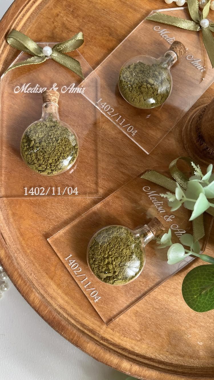 Small glass bottles of green herbs on personalized acrylic plaques on a wooden tray