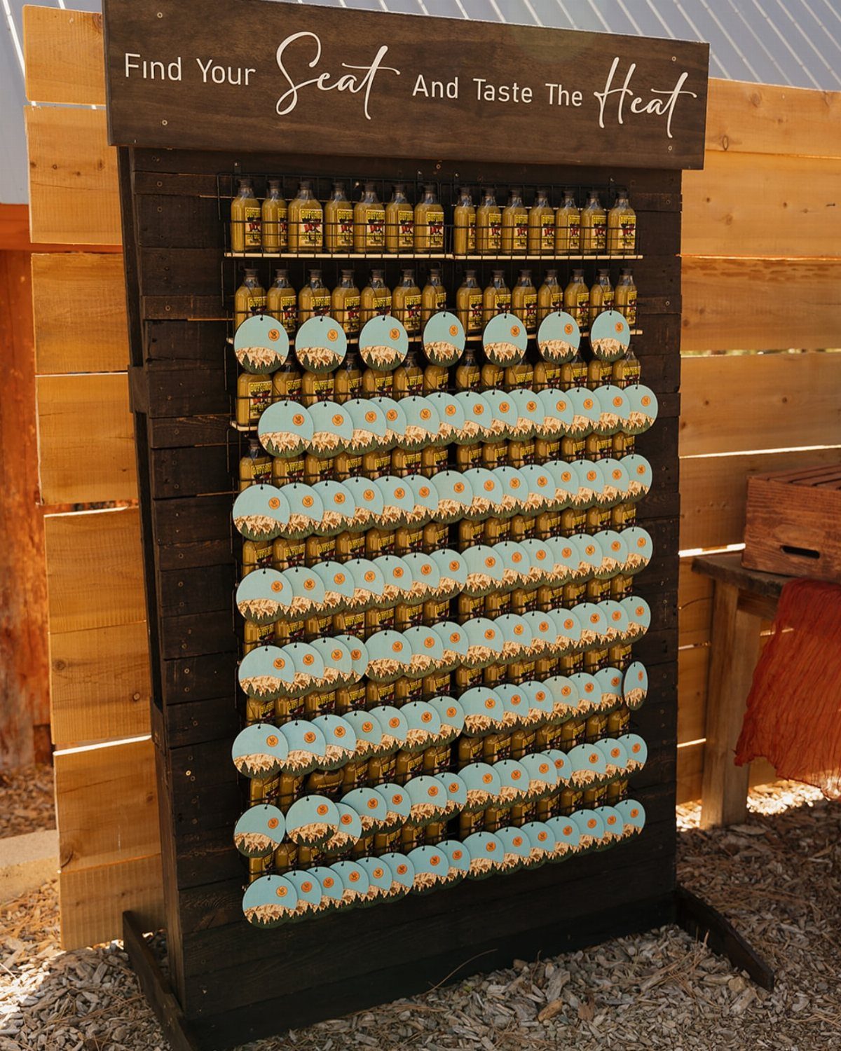 Small hot sauce bottles with blue tags on a wooden display stand