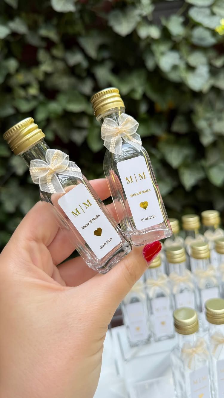 Small clear glass bottles with gold caps and cream bows as wedding favors.