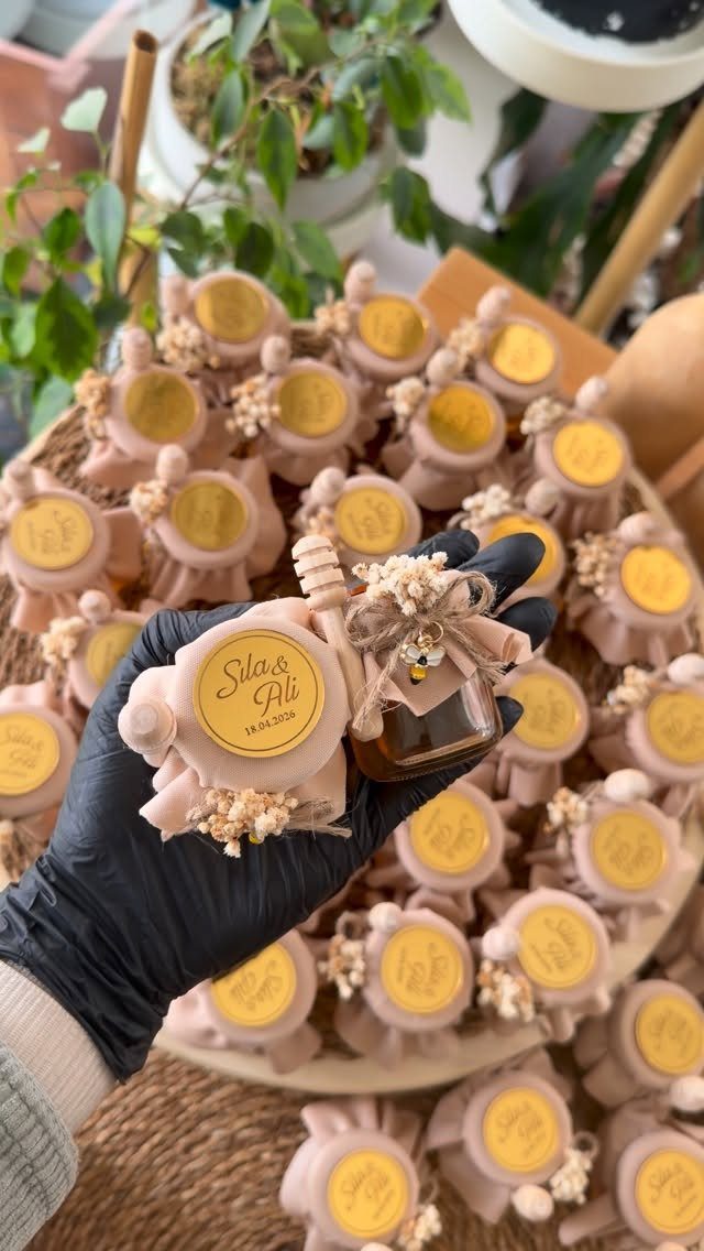 Small honey jars with pink fabric wraps and dried flowers for wedding favors.