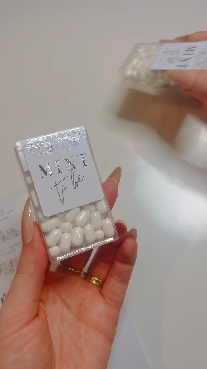 Clear plastic mint containers with custom labels reading MINT to be held in hand.