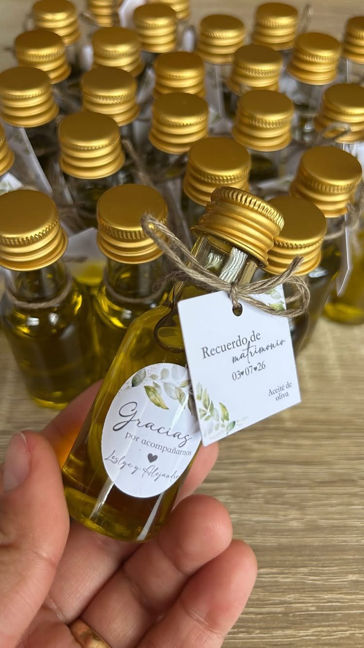 Small glass bottles of olive oil with gold caps and personalized wedding tags.
