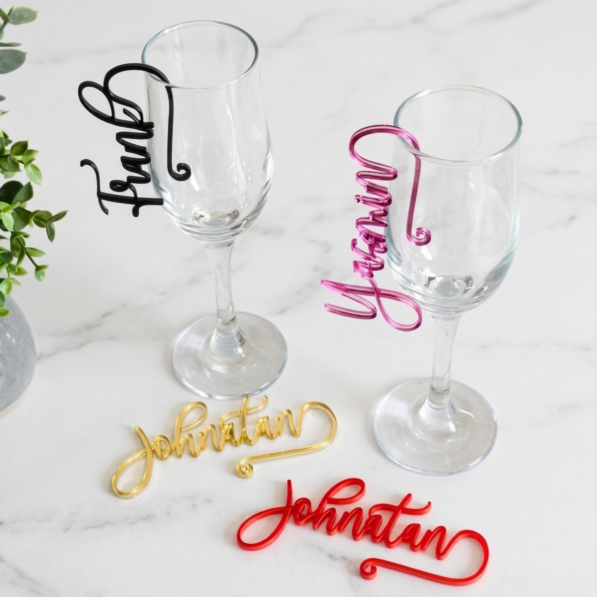 Personalized name drink charms in various colors clipped to clear wine glasses.