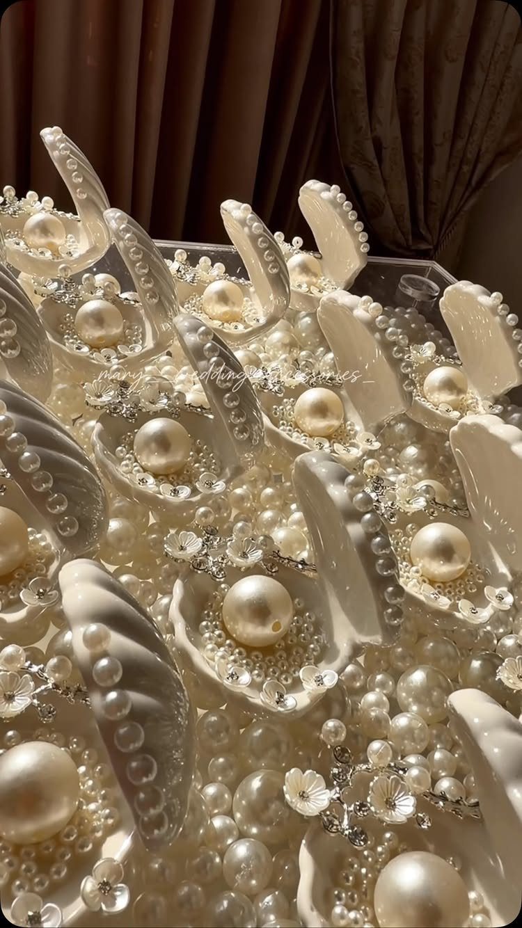 White ceramic oyster shells with pearls and crystals arranged as bridal shower favors.