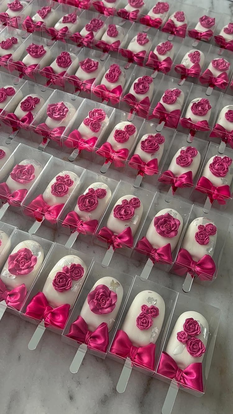 White chocolate cake pops with pink frosting roses and satin bows in packaging